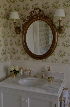 a bathroom sink with a mirror above it and two lamps on either side of the sink