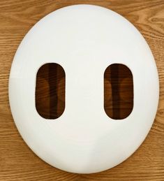 a close up of a white button on a wooden surface with two holes in the middle