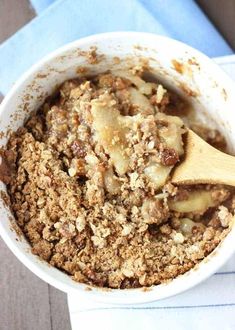 a white bowl filled with food on top of a blue napkin next to a wooden spoon