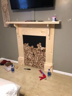 there is a fireplace with firewood stacked on it and the tv mounted above it