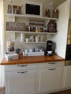 a kitchen with white cupboards and shelves filled with bread, pastries and coffee