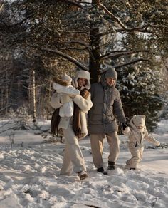 a man and woman walking in the snow with two small children on their shoulders while holding hands