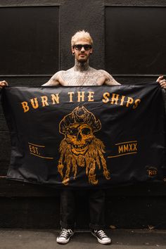 a man holding up a black banner that says burn the ship with a skull on it