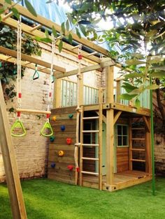 an outdoor play area with swings, climbing bars and a wooden structure in the grass