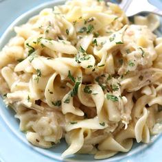 a blue plate topped with pasta covered in sauce and garnished with parsley