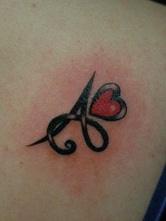 a tattoo on the back of a woman's shoulder with scissors and a heart