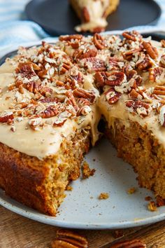 a carrot cake with frosting and pecans on top is cut in half to show the inside