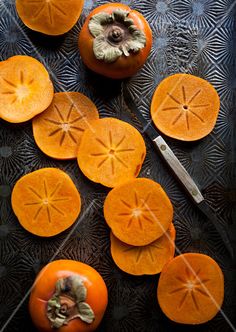 several oranges cut in half on a table with a knife and some other fruit