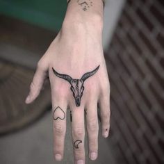 a person's hand with a tattoo on it and a cow skull in the middle