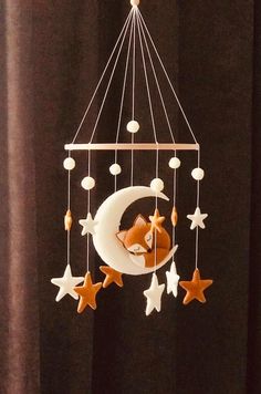 a baby crib mobile with a sleeping fox on the moon and stars hanging from it