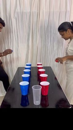 two people standing at a table with cups on it