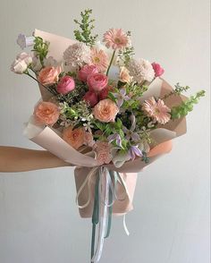 a bouquet of flowers is wrapped in brown paper and tied with a ribbon on the end