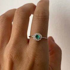 a woman's hand with an emerald and diamond ring