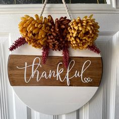 a wooden sign that says, thank you and two pine cones hanging from the front door