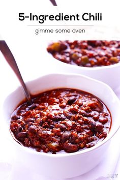 two white bowls filled with chili on top of a table