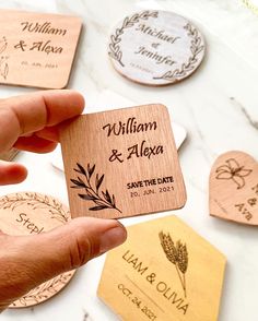 a person holding up a wooden save the date magnet with leaves on it and other personalized coasters