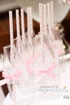 several empty wine bottles with pink bows and straws in them are lined up on a table