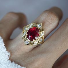 a woman's hand with a gold ring and a red stone in the middle