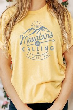 Introducing our "The Mountains Calling And I Must Go" Graphic Tee, a perfect choice for adventure enthusiasts and outdoor lovers. Most t shirt colors are 52/48 cotton/poly blend. White and Cream tees are 100% cotton, Ash tees are 99/1 cotton/poly. Available in various sizes, it's an excellent addition to outdoor retail stores and adventure-themed boutiques. Encourage your customers to answer the call of the mountains with our "The Mountains Calling And I Must Go" Graphic Tee. By Kissed Apparel.M Relaxed Fit Tops With Letter Print For Outdoor Activities, Blue Tops With Screen Print For Outdoor Activities, Graphic Tee With Text Print For Outdoor Activities, Blue Screen Print Tops For Outdoor Activities, Graphic Tee Tops With Text Print For Outdoor Activities, Blue Screen Printed Tops For Outdoor Activities, Crew Neck Cotton Top For Hiking, Relaxed Fit Text Print Top For Outdoor Activities, Cotton T-shirt With Letter Print For Outdoor Activities