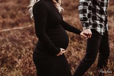 a pregnant woman standing next to a man in a field