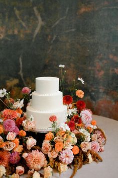 a wedding cake surrounded by flowers on a table