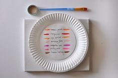 a white paper plate with different colored crayons on it next to a pair of scissors