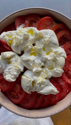 a bowl filled with tomatoes and cheese on top of a table