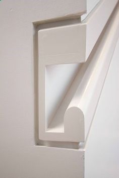 the corner of a wall with a white door handle and an opening for a window