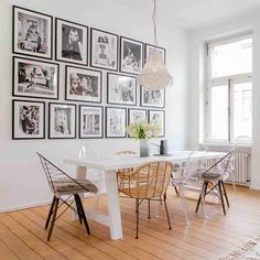 a dining room table with chairs and pictures on the wall in front of it's windows