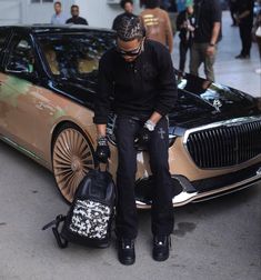 a man sitting on the hood of a car with his luggage in front of him