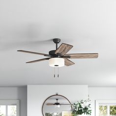 a ceiling fan in the middle of a living room with white walls and wood floors