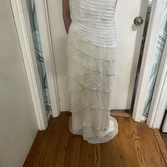 a woman is standing in front of a door wearing a white dress with ruffles