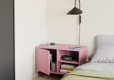 a bedroom with a bed, nightstand and lamp on the side table in front of it