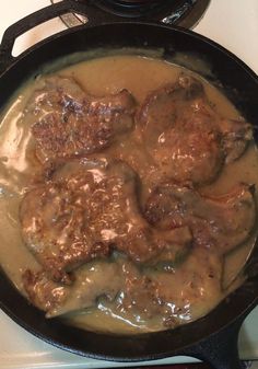 some meatballs and gravy are in a skillet on the stove top