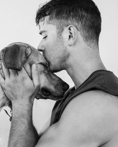 a man is kissing his dog on the nose