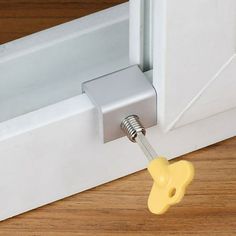 a door handle is attached to the side of a white door with a yellow push button