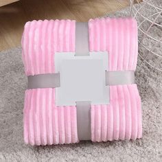 a pink blanket with a silver ribbon around it and a mirror on the floor next to it