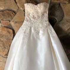 a wedding dress hanging on a stone wall