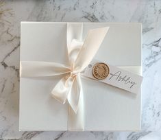 a close up of a white box with a ribbon on it and a seal in the middle