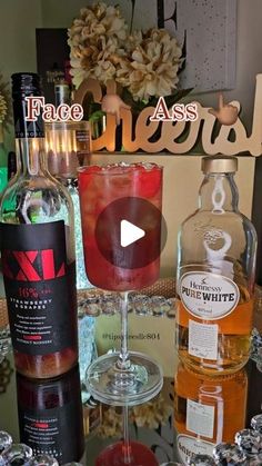 two bottles of alcohol sitting on top of a table next to wine glasses and candles