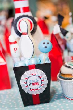 a table topped with cupcakes and bowling pins