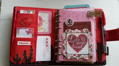 an open red planner book with lots of things inside and writing on the pages in it