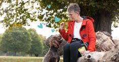 an older woman sitting on a rock with her dog and butterflies in front of her