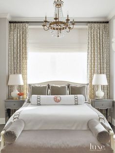 a large bed sitting under a chandelier in a bedroom next to two lamps