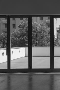 a black and white photo of an empty room with sliding glass doors looking out onto the street