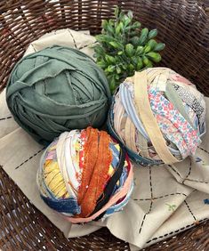 three balls of fabric sitting on top of a basket next to a potted plant