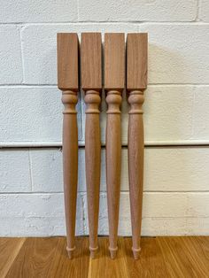 three wooden candlesticks are lined up against a brick wall