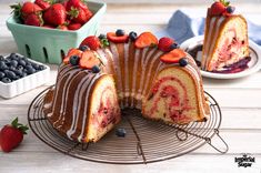 a bundt cake with strawberries and blueberries on top is sitting on a wire rack