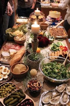 a table filled with lots of different types of food and candles on top of it