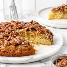 a piece of pecan cake on a plate with the rest of the cake in the background